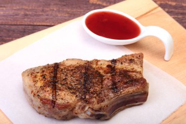 ızgara domuz eti ile kızılcık sosu ahşap tahta üzerinde plaka üzerinde