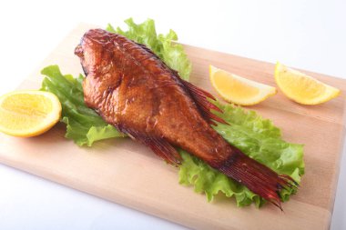 Füme balık ve beyaz arka plan üzerinde izole tahta kesme tahta üzerinde yeşil marul yaprakları limon.