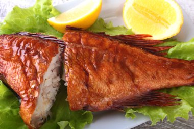 Füme balık ve beyaz arka plan üzerinde izole tahta kesme tahta üzerinde yeşil marul yaprakları limon.