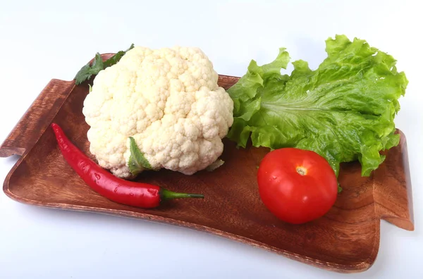 Свежая цветная капуста, помидоры, листья салата и другие овощи на деревянной доске. Готовы к приготовлению. Вегетарианская еда . — стоковое фото