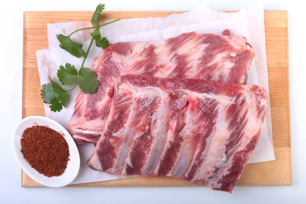 Raw pork ribs with herbs and spices on wooden board. Ready for cooking. — Stock Photo, Image