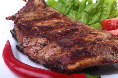 Domuz kaburga ızgara ve biber domates ile beyaz tabağına marul yaprakları