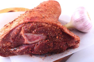 Çiğ domuz knuckle, sarımsak ve baharat bir kesme tahtası üzerinde. Seçici odak. Hazır yemek pişirmek için.