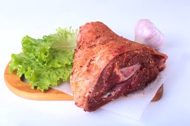 Çiğ domuz knuckle, sarımsak, baharat ve marul yaprakları bir kesme tahtası üzerinde. Seçici odak. Hazır yemek pişirmek için.