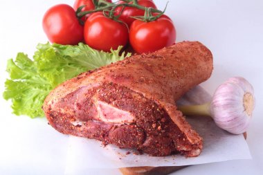 Çiğ domuz knuckle ve sebze, sarımsak, domates baharat ve marul yaprakları bir kesme tahtası üzerinde. Seçici odak. Hazır yemek pişirmek için.