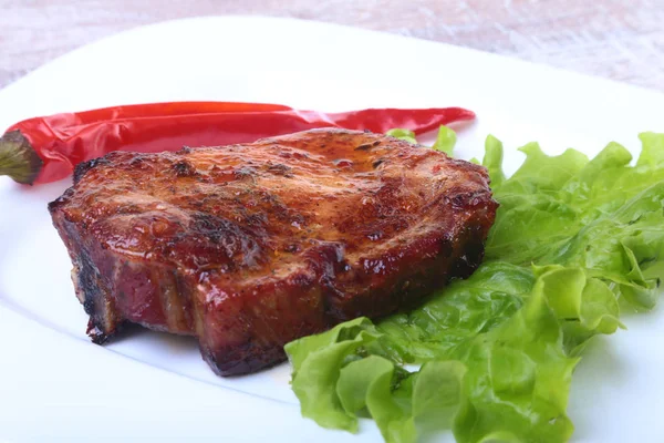 Steak von gegrilltem Fleisch und Chili mit Tomaten, Salatblättern auf weißem Teller. — Stockfoto