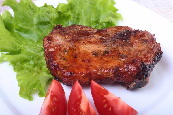 Стейк з м'яса на грилі та перець чилі з помідорами, листям салату на білій тарілці . — стокове фото