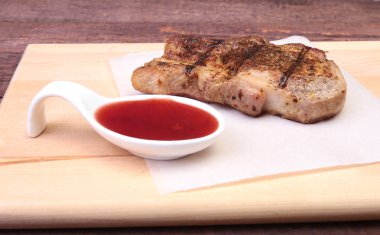 ızgara domuz eti ile kızılcık sosu ahşap tahta üzerinde plaka üzerinde