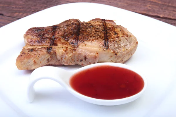 Chuleta de cerdo a la parrilla con salsa de arándano en plato sobre tabla de madera — Foto de Stock