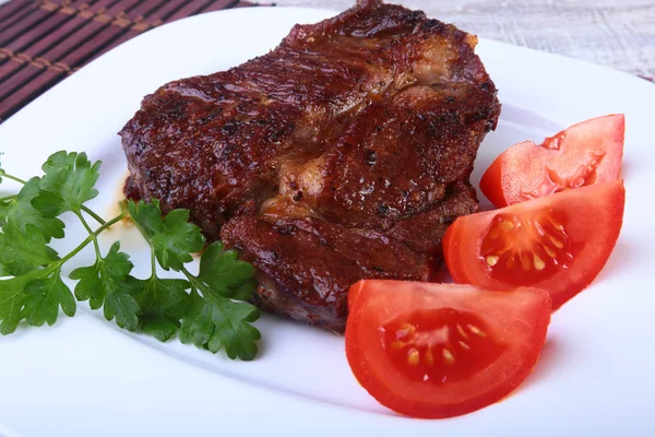 Жареная говядина стейк с помидорами, и горячий азиатский соус чили чеснок на тарелке на деревянном фоне . — стоковое фото