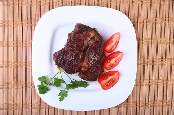 Steak sapi panggang dengan tomat, dan saus bawang putih Asia panas di piring dengan latar belakang kayu . — Stok Foto