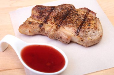 ızgara domuz eti ile kızılcık sosu ahşap tahta üzerinde plaka üzerinde