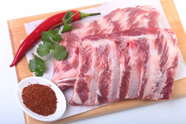 Raw pork ribs with herbs and spices on wooden board. Ready for cooking. — Stock Photo, Image