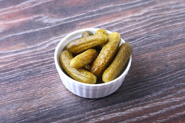 Bowl with pickled gherkins, cucumbers on wooden background close up. Pickles. — Stock Photo, Image