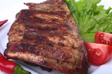 Domuz kaburga ızgara ve biber domates ile beyaz tabağına marul yaprakları