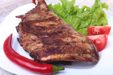 Domuz kaburga ızgara ve biber domates ile beyaz tabağına marul yaprakları