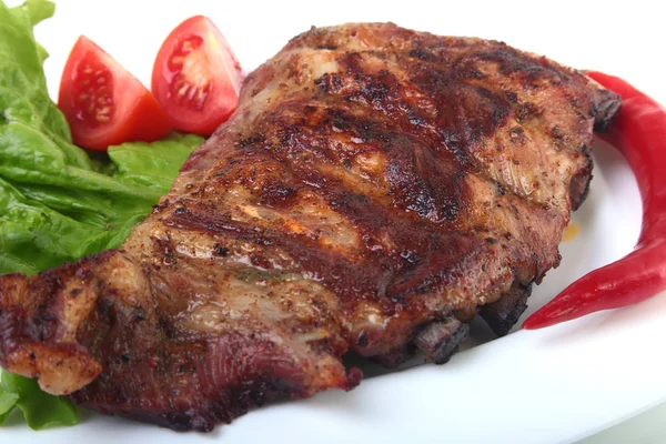 Rusuk babi di panggangan dan cabai dengan tomat, daun selada di piring putih — Stok Foto