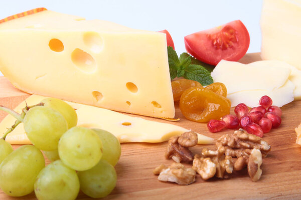 Ассортимент сыра с фруктами, виноградом, орехами и сырным ножом на подносе
.