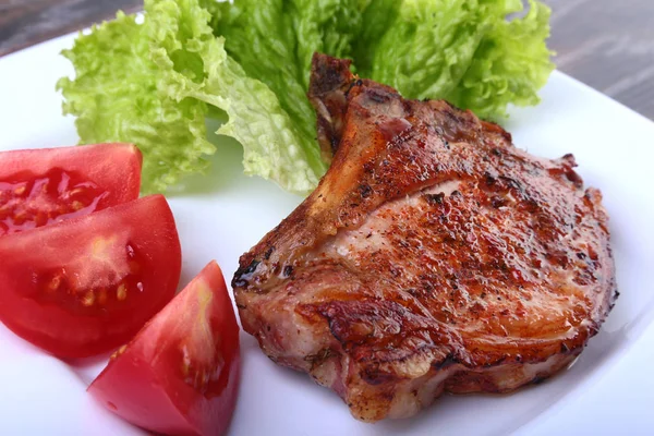 Daging babi panggang dengan tomat, daun selada dan saus tomat di atas piring . — Stok Foto