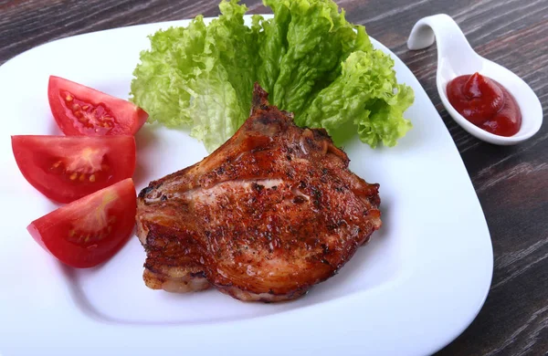 Daging babi panggang dengan tomat, daun selada dan saus tomat di atas piring . — Stok Foto