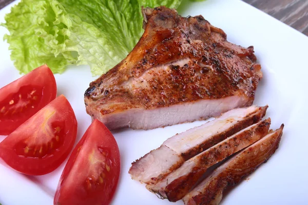 Daging babi panggang dengan tomat, daun selada dan saus tomat di atas piring . — Stok Foto