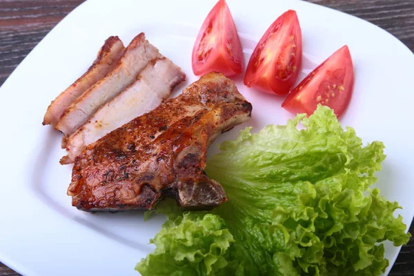 Daging babi panggang dengan tomat, daun selada dan saus tomat di atas piring . — Stok Foto