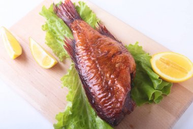 Füme balık ve beyaz arka plan üzerinde izole tahta kesme tahta üzerinde yeşil marul yaprakları limon.