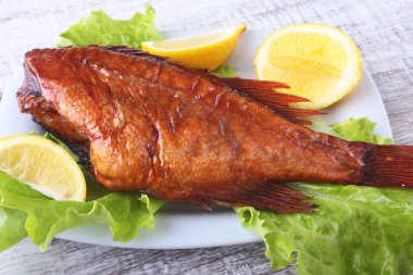 Füme balık ve beyaz arka plan üzerinde izole tahta kesme tahta üzerinde yeşil marul yaprakları limon.