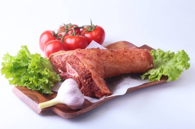 Çiğ domuz knuckle ve sebze, sarımsak, domates baharat ve marul yaprakları bir kesme tahtası üzerinde. Seçici odak. Hazır yemek pişirmek için.