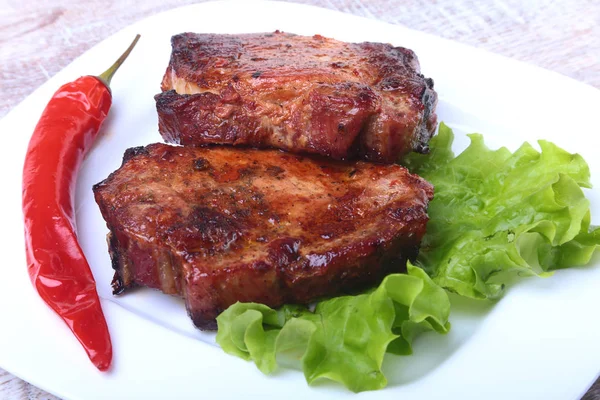 Steak daging panggang dan cabai dengan tomat, daun selada di piring putih . — Stok Foto