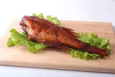 Füme balık ve beyaz arka plan üzerinde izole tahta kesme tahta üzerinde yeşil marul yaprakları limon.