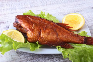 Füme balık ve beyaz arka plan üzerinde izole tahta kesme tahta üzerinde yeşil marul yaprakları limon.