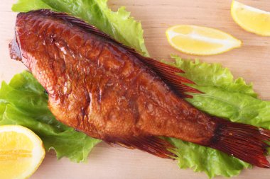 Füme balık ve beyaz arka plan üzerinde izole tahta kesme tahta üzerinde yeşil marul yaprakları limon.