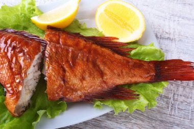 Füme balık ve beyaz arka plan üzerinde izole tahta kesme tahta üzerinde yeşil marul yaprakları limon.