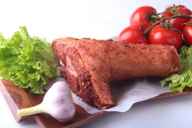 Çiğ domuz knuckle ve sebze, sarımsak, domates baharat ve marul yaprakları bir kesme tahtası üzerinde. Seçici odak. Hazır yemek pişirmek için.
