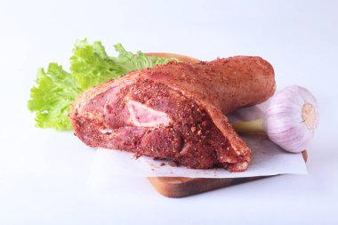 Çiğ domuz knuckle, sarımsak, baharat ve marul yaprakları bir kesme tahtası üzerinde. Seçici odak. Hazır yemek pişirmek için.