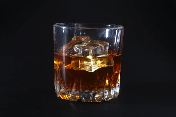 Glass of whiskey or bourbon with ice on black stone table. — Stock Photo, Image