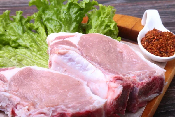 Bife cru de porco com especiarias Deixa a alface na tábua de corte de madeira. Pronto para cozinhar . — Fotografia de Stock