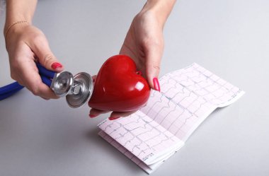 Kadın doktor eller kırmızı oyuncak kalp ve stetoskop tutun. Kardiyo therapeutist, aritmi kavramı