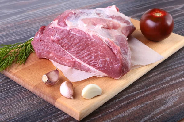 Otlar, sarımsak, baharatlar ve domates yemek pişirmek için hazır ahşap tahta üzerinde çiğ domuz biftek. Seçici odak.