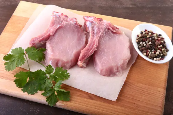 Raw pork steak with spices Leaves of coriander on wooden cutting board. Ready for cooking. — Stock Photo, Image