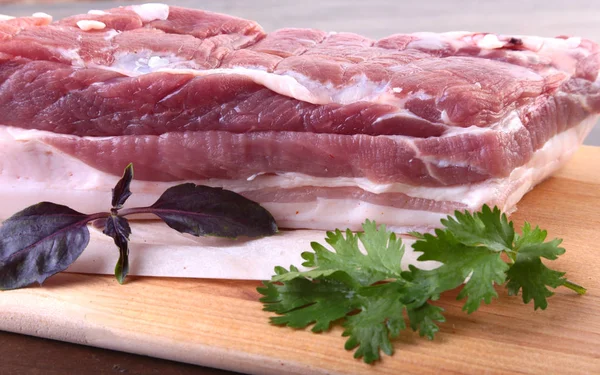 Raw pork meat with spices Leaves of coriander on wooden cutting board. Ready for cooking. — Stock Photo, Image