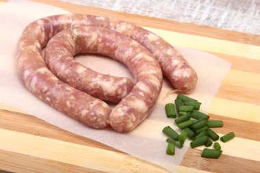 Ahşap arka plan üzerinde baharatlar ile ev yapımı çiğ sosis.