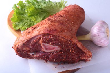 Çiğ domuz knuckle, sarımsak, baharat ve marul yaprakları bir kesme tahtası üzerinde. Seçici odak. Hazır yemek pişirmek için.