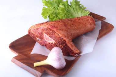 Çiğ domuz knuckle, sarımsak, baharat ve marul yaprakları bir kesme tahtası üzerinde. Seçici odak. Hazır yemek pişirmek için.