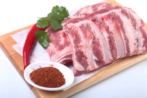 Raw pork ribs with herbs and spices on wooden board. Ready for cooking. — Stock Photo, Image