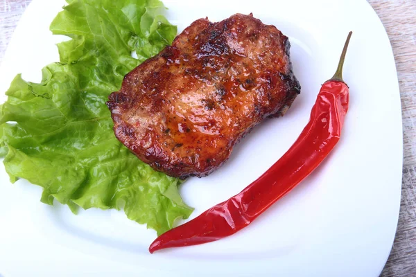 Stek z grillowanego mięsa i papryka chili z pomidorów, sałaty pozostawia na białym talerzu. — Zdjęcie stockowe