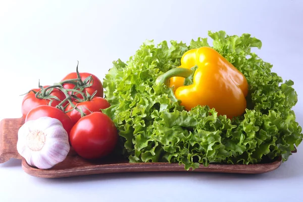 Свіжі овочі перець болгарський, помідор, часник з листям салату. Ізольовані на білому тлі. Вибірковий фокус . — стокове фото
