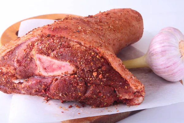 Çiğ domuz knuckle, sarımsak ve baharat bir kesme tahtası üzerinde. Seçici odak. Hazır yemek pişirmek için.