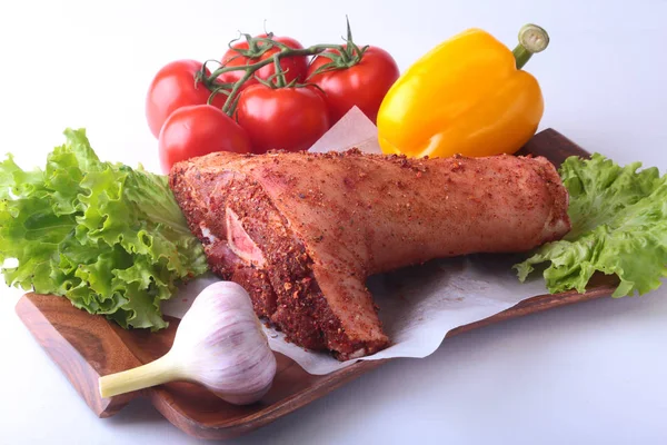 Çiğ domuz knuckle ve sebze, sarımsak, domates, dolmalık biber. baharat ve marul yaprakları bir kesme tahtası üzerinde. Seçici odak. Hazır yemek pişirmek için.